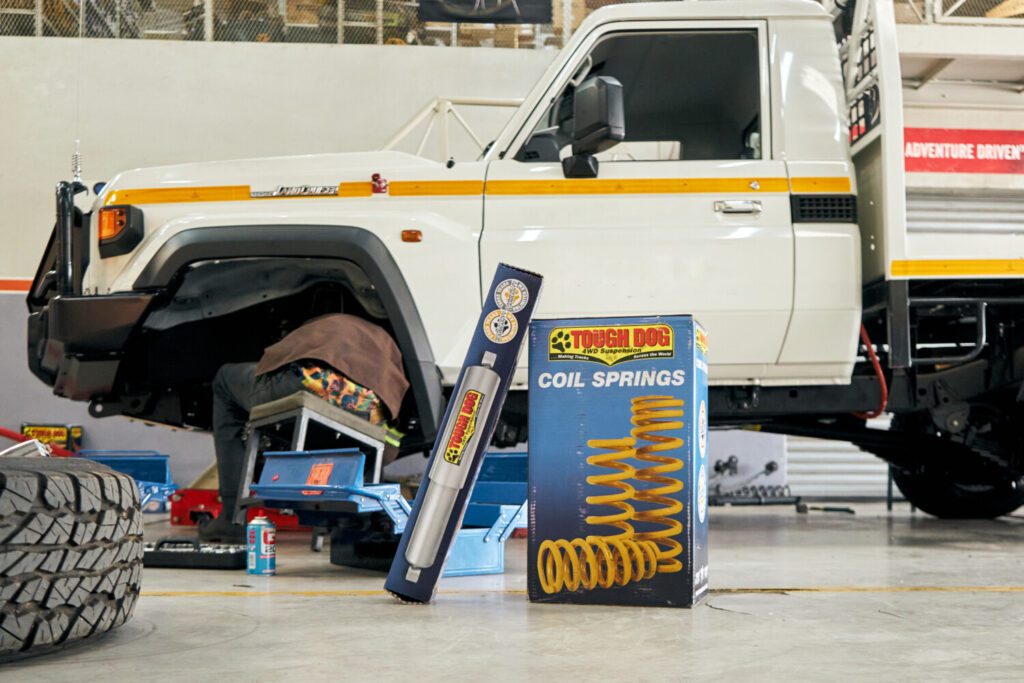 Tough Dog shock absorber and coil spring boxes displayed beside a Land Cruiser in the Hi-Range workshop