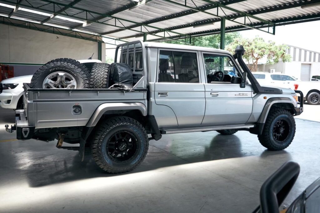 Silver Toyota Land Cruiser 79 double cab fitted with a snorkel and dual spare wheels in the workshop